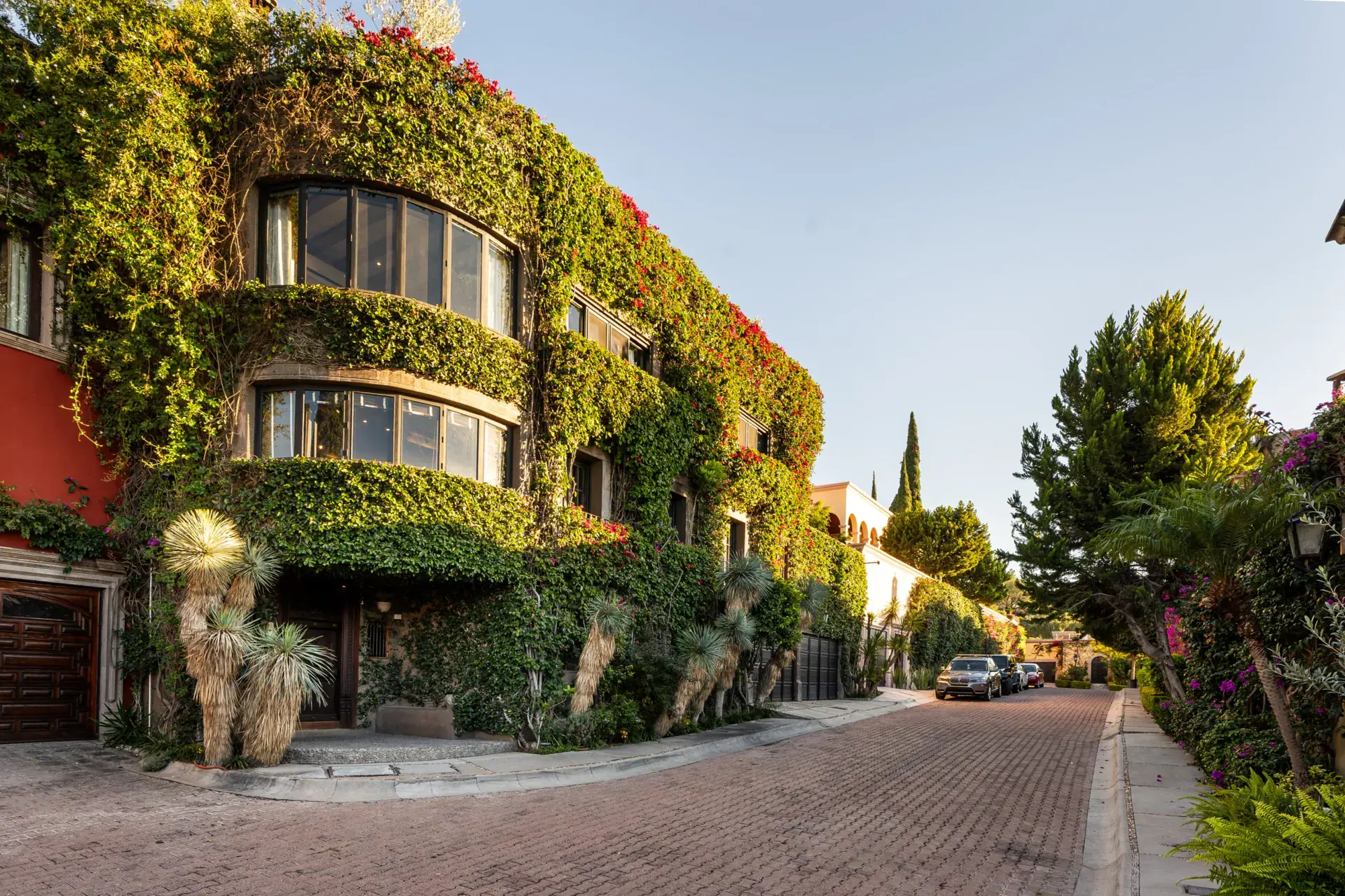 Casa Zen, ivy-covered facade with rounded bay windows on a brick street, San Miguel de Allende