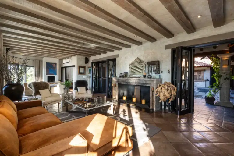 Casa Zen, living room with a stone fireplace, orange leather sofa and beamed ceiling, San Miguel de Allende