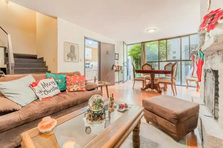 Casitas Terraplen, living room with brown sofas, a Christmas-decorated fireplace and a glass wall to a bamboo garden, San Miguel de Allende