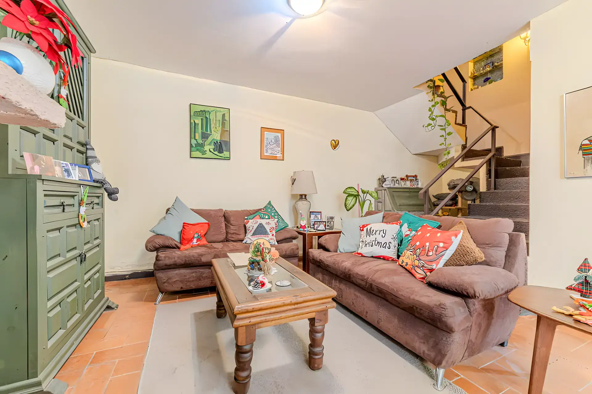 Casitas Terraplen, living room with brown sofas, a green carved cabinet and a staircase, San Miguel de Allende