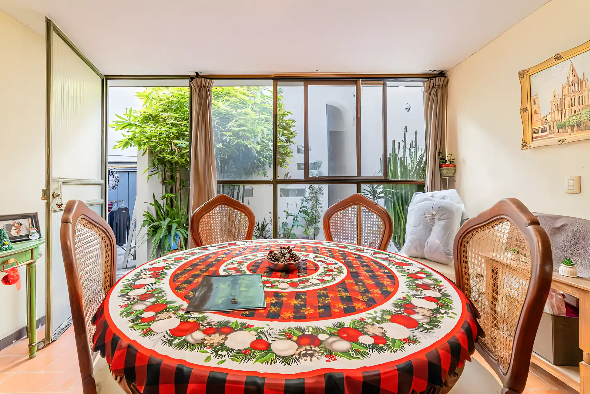 Casitas Terraplen, round dining table with a Christmas cloth and cane-back chairs by a glass wall onto a garden, San Miguel de Allende
