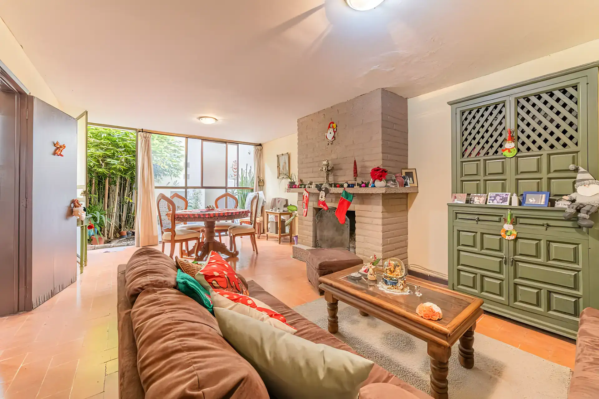 Casitas Terraplen, living room and dining area with a brick fireplace, a green lattice cabinet and a glass wall to the garden, San Miguel de Allende