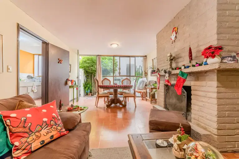 Casitas Terraplen, living room with a brick fireplace, a green lattice cabinet and a view to the dining area and a bedroom beyond, San Miguel de Allende