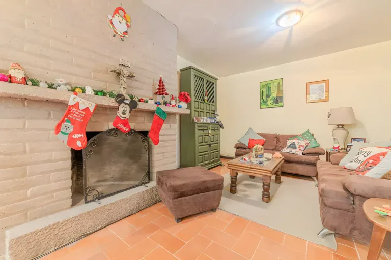 Casitas Terraplen, brick fireplace with Christmas stockings and a green lattice cabinet beside a brown sofa, San Miguel de Allende