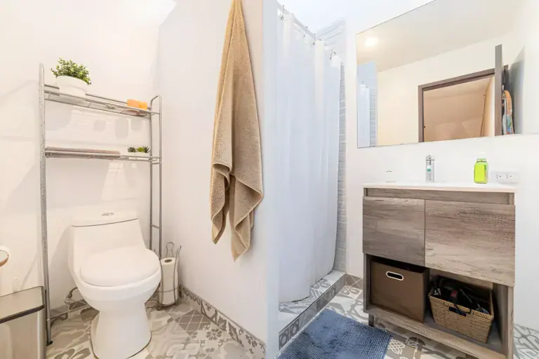 Casitas Terraplen, bathroom with a toilet, a shower with a white curtain and a wood vanity, San Miguel de Allende