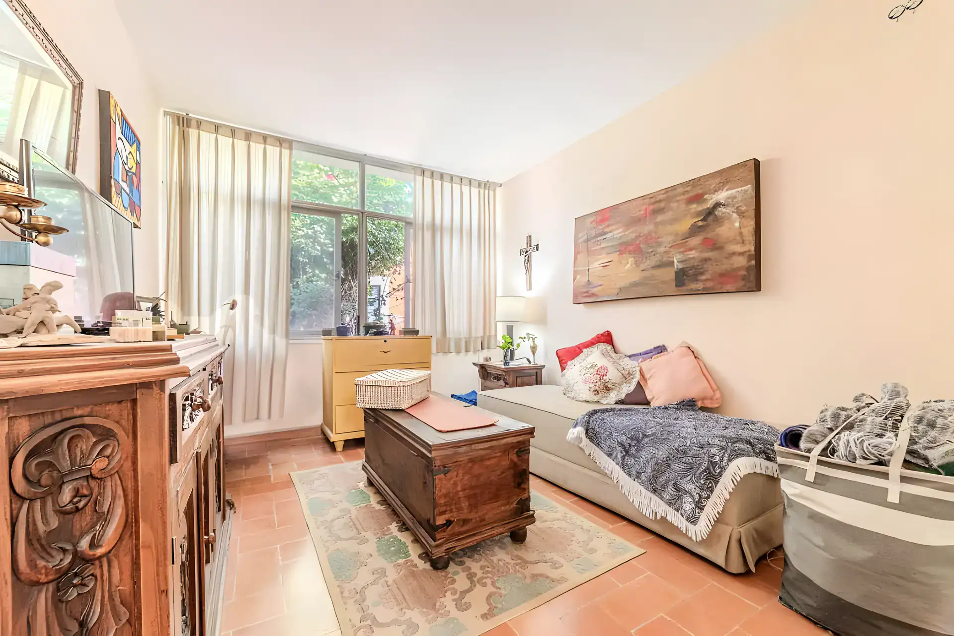Casitas Terraplen, bedroom with a carved wood chest and sideboard, a daybed and an abstract painting, San Miguel de Allende