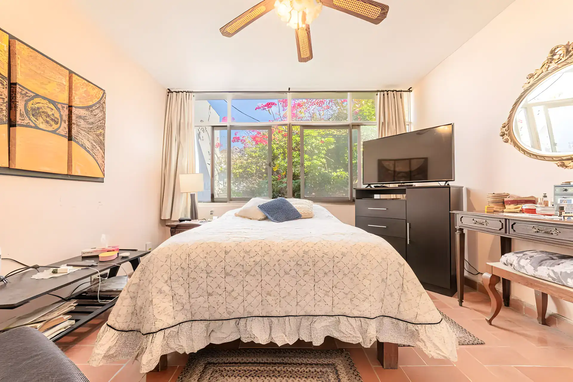 Casitas Terraplen, bedroom with a ruffled white bedspread, a ceiling fan, a television and a window to a flowering tree, San Miguel de Allende