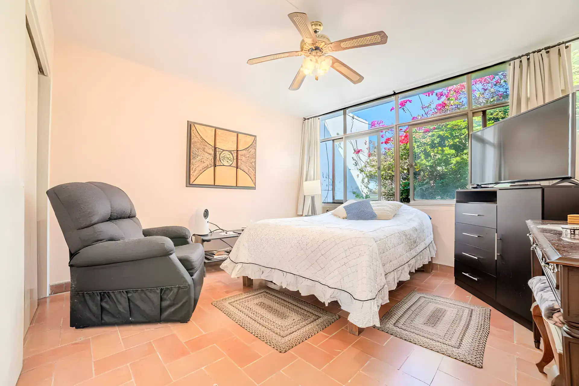 Casitas Terraplen, bedroom with a leather recliner, a bed, a television and a ceiling fan and a window to bougainvillea, San Miguel de Allende