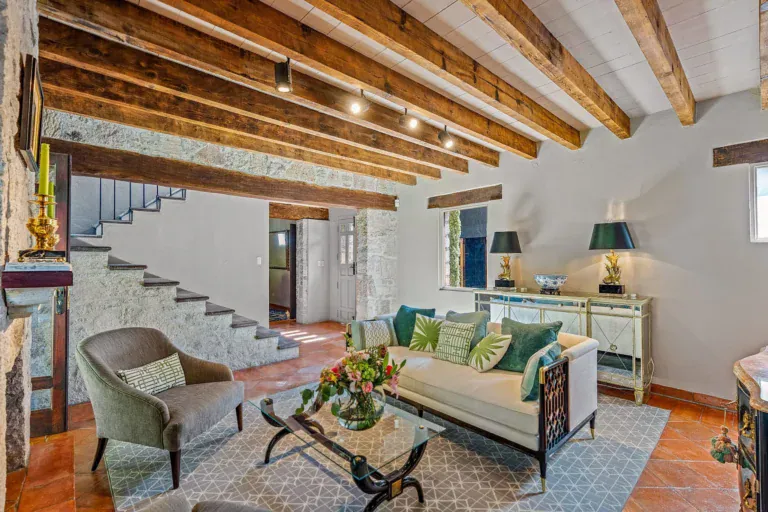 Cuesta de San Jose 22, living room with a cream sofa, a velvet armchair and a stone staircase behind, San Miguel de Allende