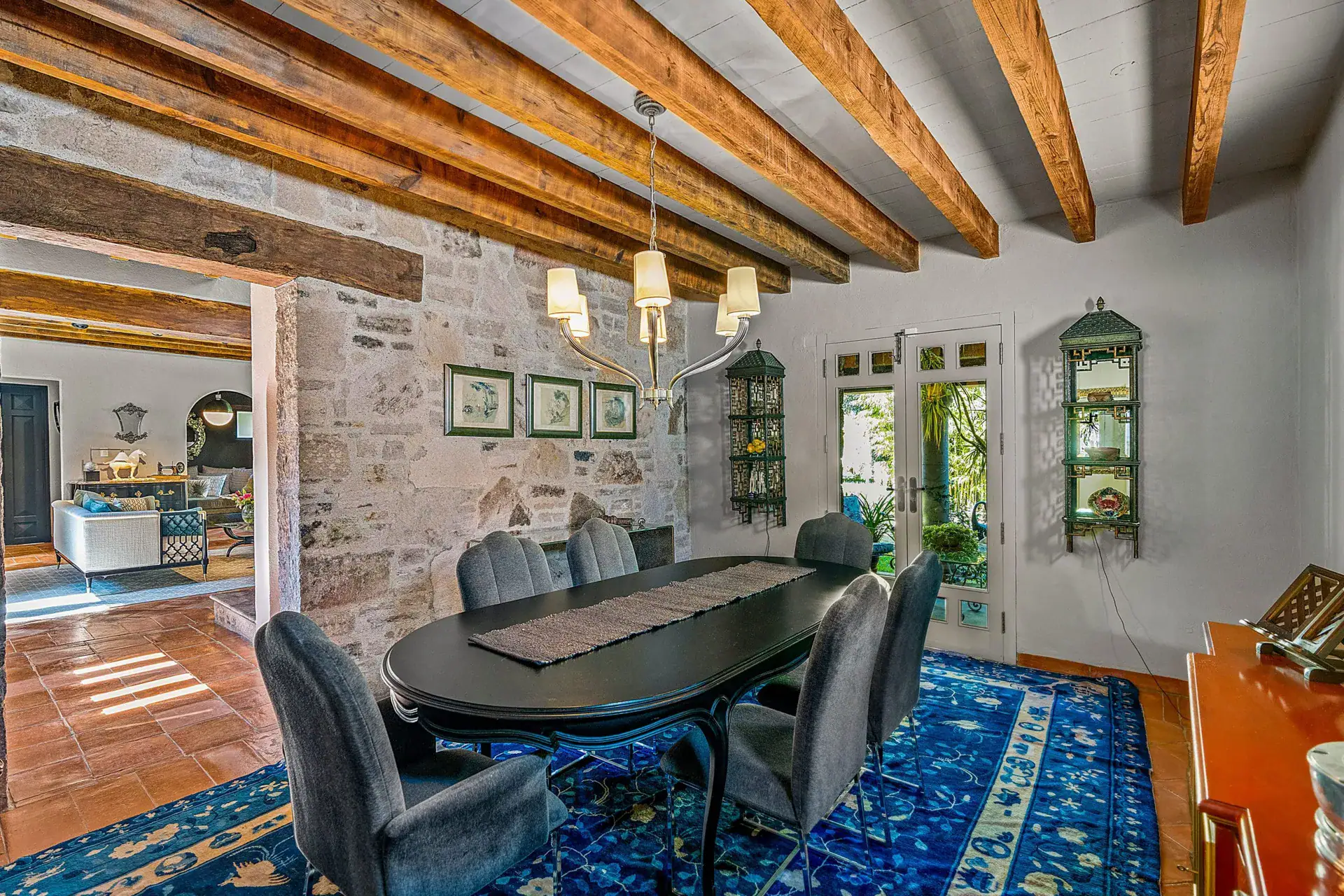 Cuesta de San Jose 22, dining room with an oval black table, gray chairs, a blue rug and a stone wall, San Miguel de Allende
