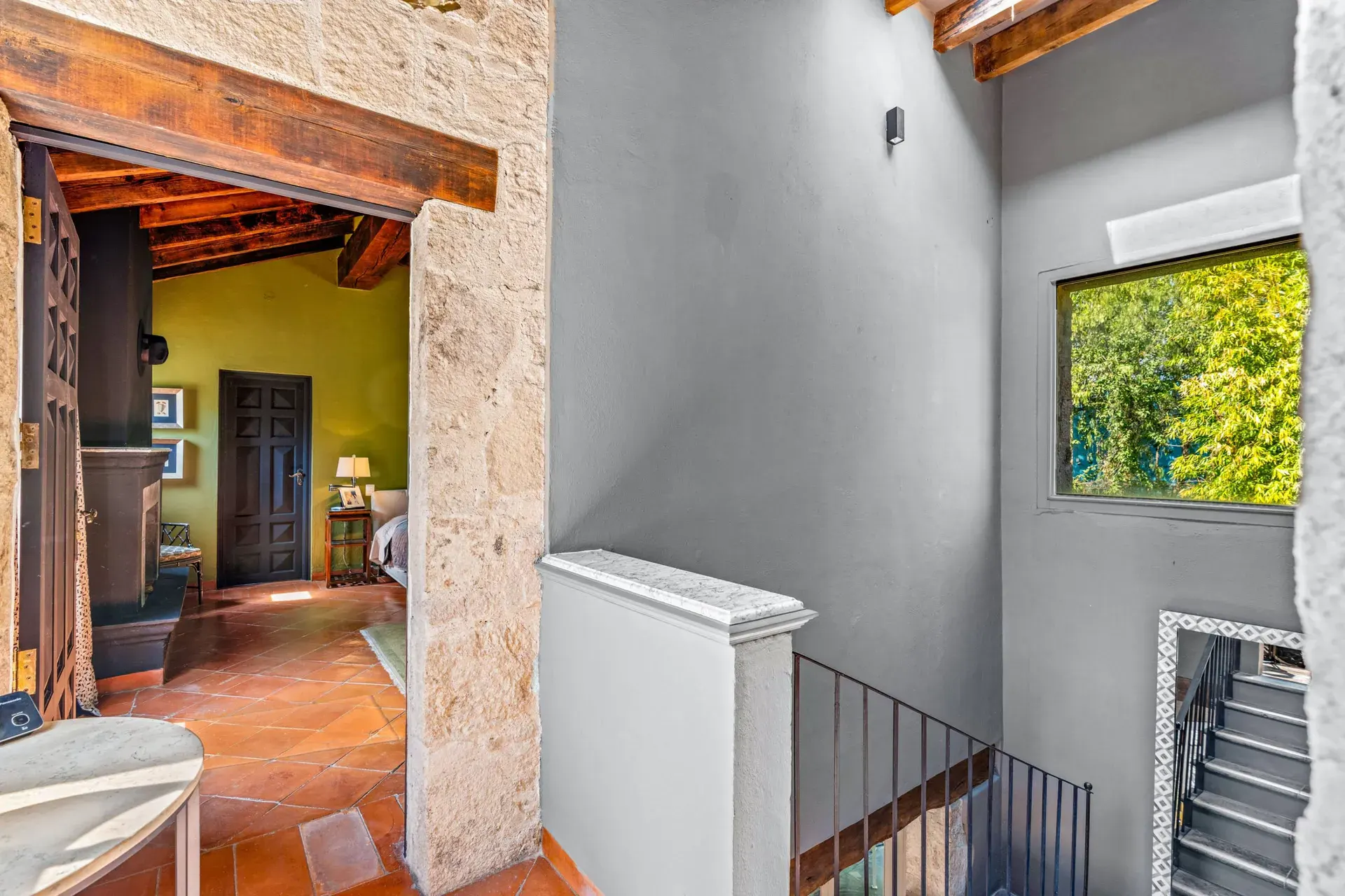 Cuesta de San Jose 22, stairway landing with a stone column, an iron railing and a view into a green bedroom, San Miguel de Allende