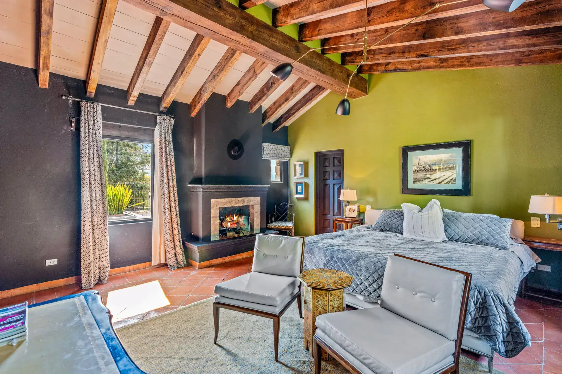 Cuesta de San Jose 22, bedroom with a stone fireplace, a black wall, a gray bedspread and two armchairs, San Miguel de Allende