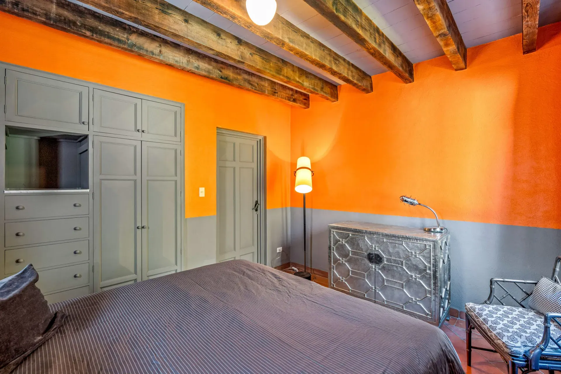 Cuesta de San Jose 22, bedroom with orange walls, a built-in wardrobe, a dresser and a dark bedspread, San Miguel de Allende