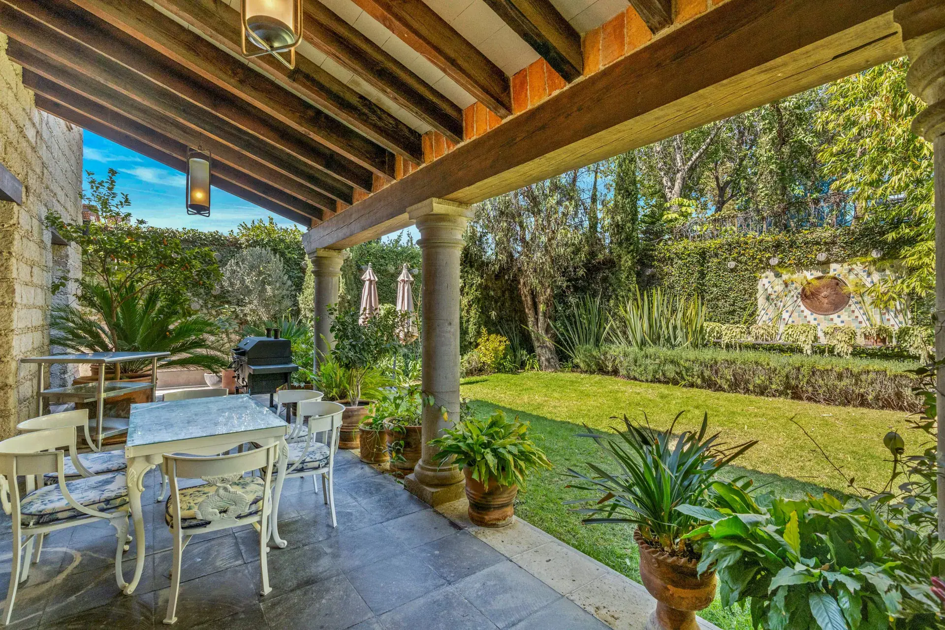 Cuesta de San Jose 22, covered terrace with a stone-tile dining table, white chairs and a view of the lawn and a grill, San Miguel de Allende