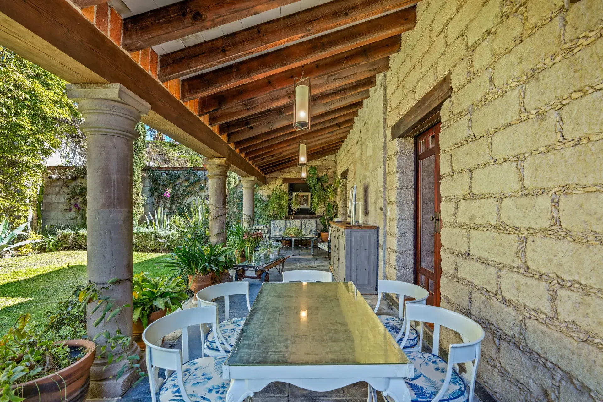 Cuesta de San Jose 22, covered terrace with a long marble-top dining table, white chairs and stone walls, San Miguel de Allende