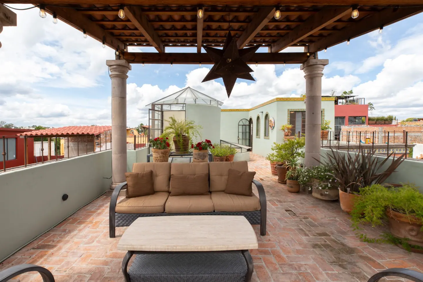 Casa Brillante, covered roof terrace with outdoor sofa and potted plants, San Miguel de Allende