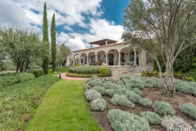 Finca Garambullos, long arcaded hacienda facade behind a lawn and lavender beds, San Miguel de Allende