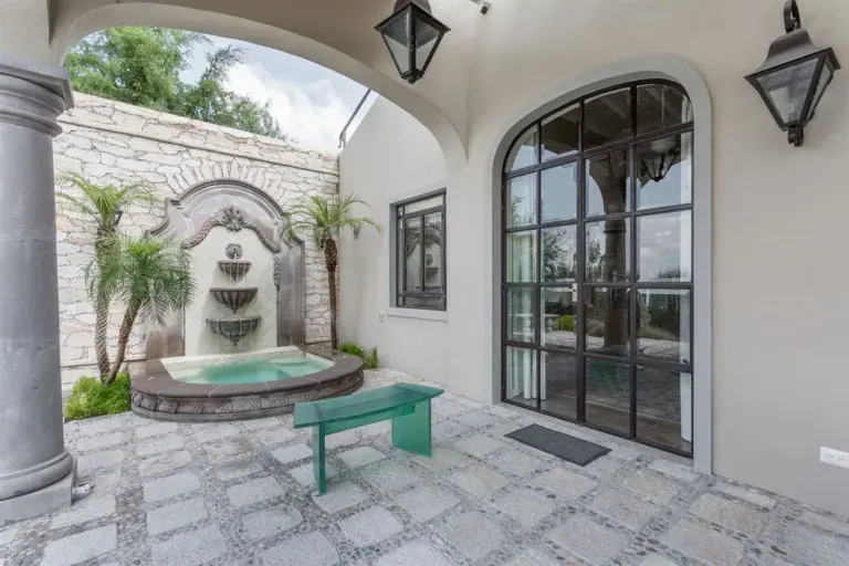 Finca Garambullos, courtyard with a stone wall fountain and a green bench, San Miguel de Allende