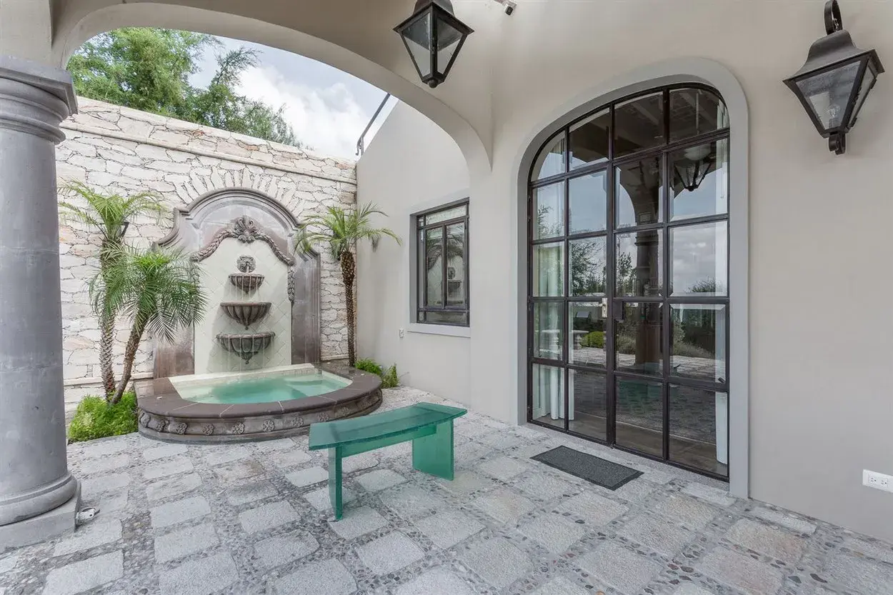 Finca Garambullos, courtyard with a stone wall fountain and a green bench, San Miguel de Allende