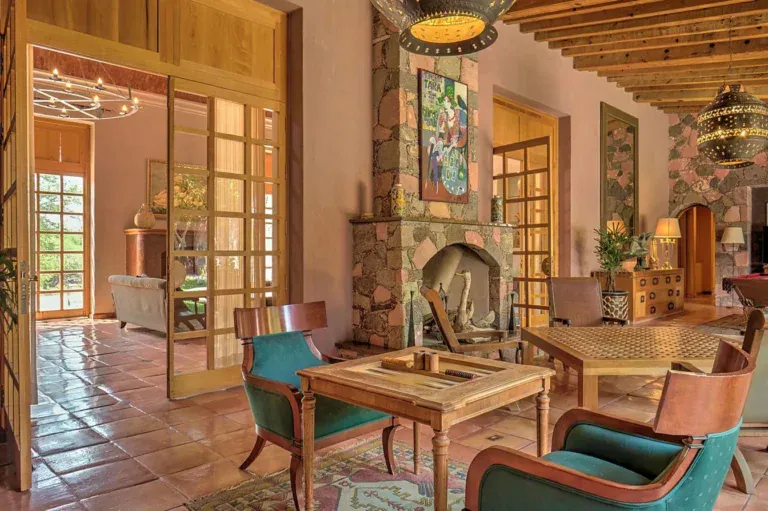 Hacienda Candelaria, living room with a stone fireplace, glass doors and a seating area, San Miguel de Allende