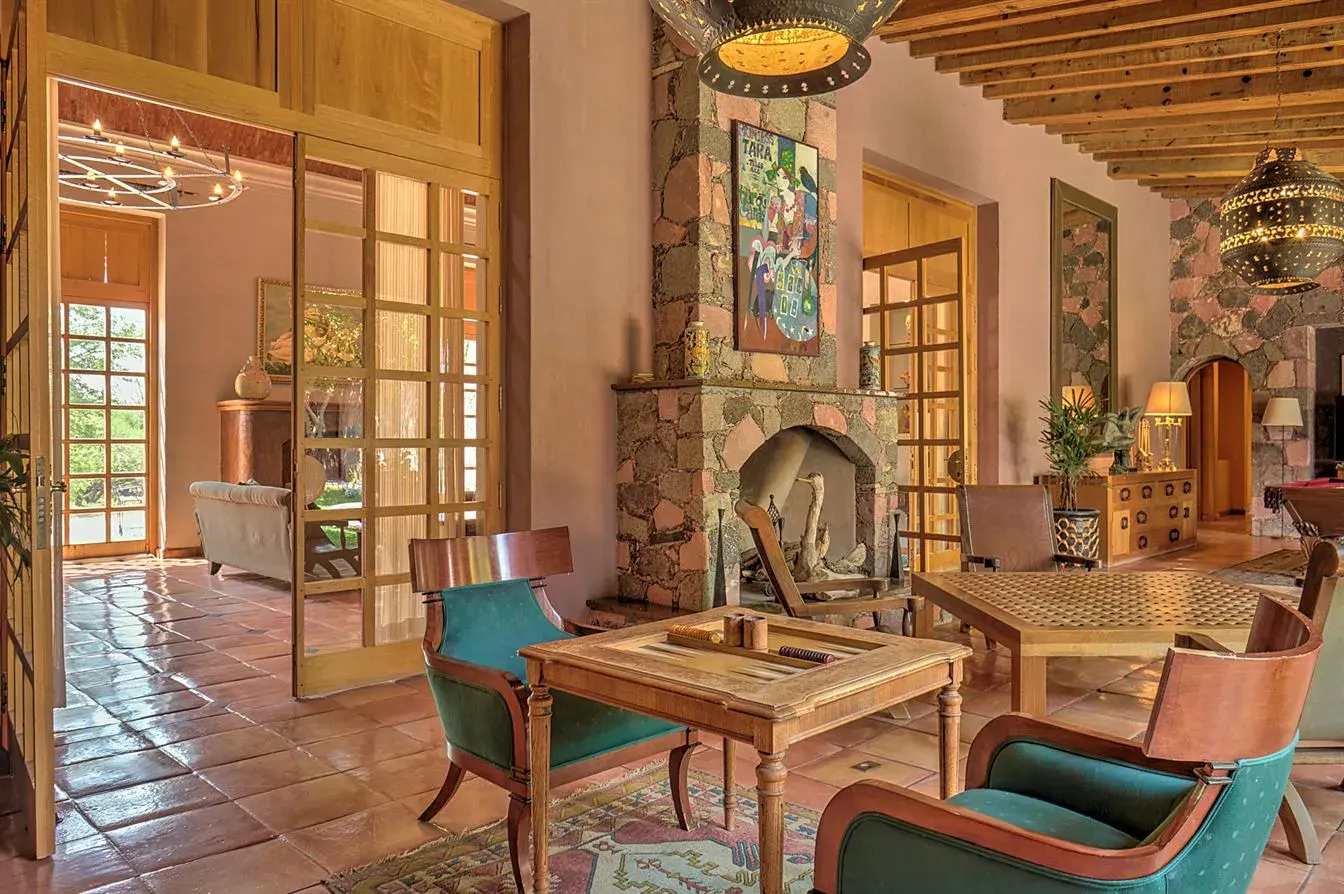 Hacienda Candelaria, living room with a stone fireplace, glass doors and a seating area, San Miguel de Allende