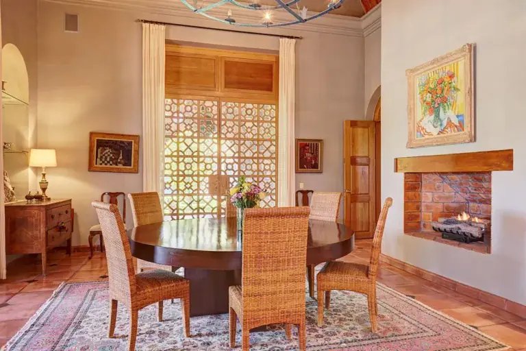 Hacienda Candelaria, dining room with a round table, wicker chairs and a latticed window, San Miguel de Allende