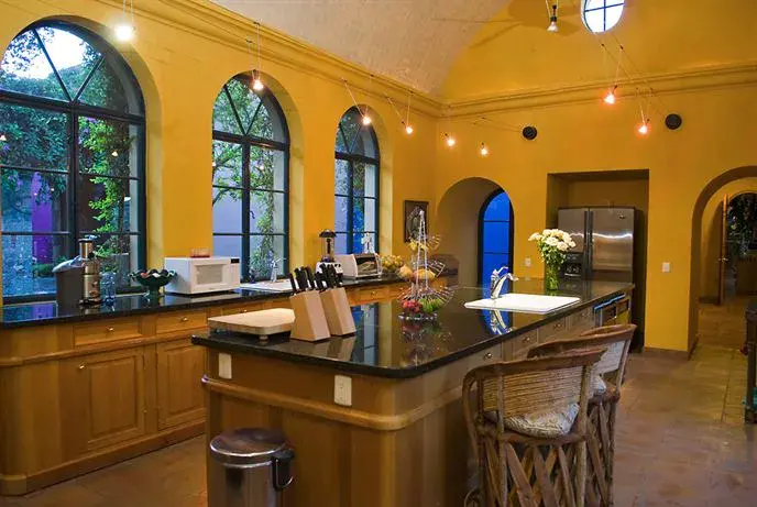 Hacienda Candelaria, kitchen with a granite island, arched windows and yellow walls, San Miguel de Allende