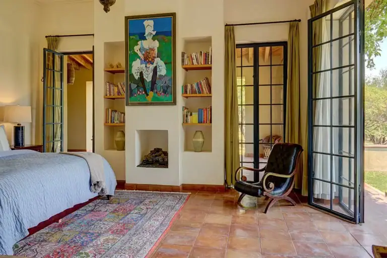 Hacienda Candelaria, bedroom with built-in shelves, a rug and glass doors to the garden, San Miguel de Allende