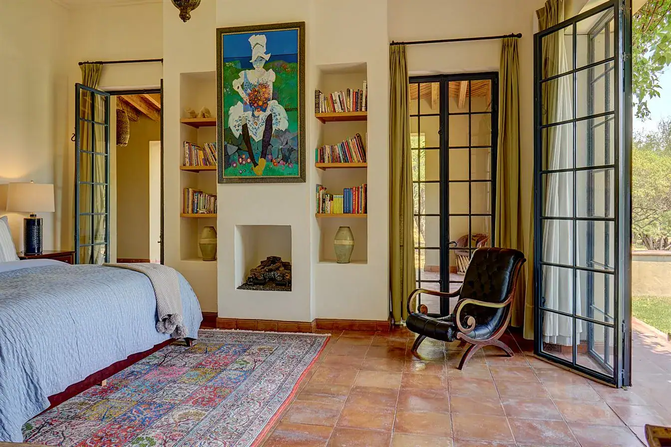 Hacienda Candelaria, bedroom with built-in shelves, a rug and glass doors to the garden, San Miguel de Allende