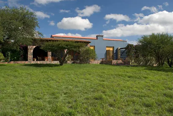 Hacienda Candelaria, house with a tile roof across a lawn under a blue sky, San Miguel de Allende