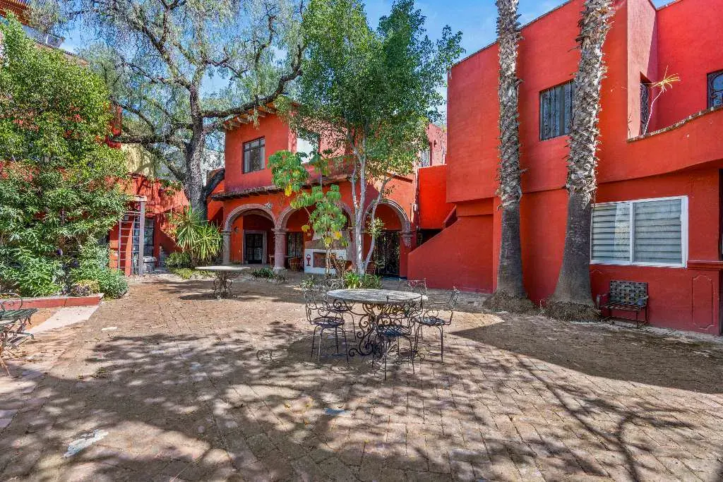 Hotel Casa Luna, courtyard with trees, tables and a red building, San Miguel de Allende