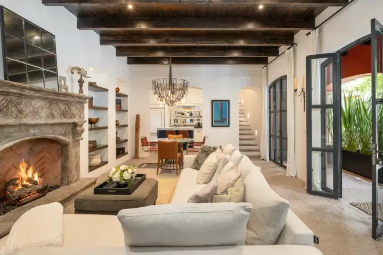 Casa Santa Mónica, living room with a stone fireplace, a white sectional and a beamed ceiling, San Miguel de Allende