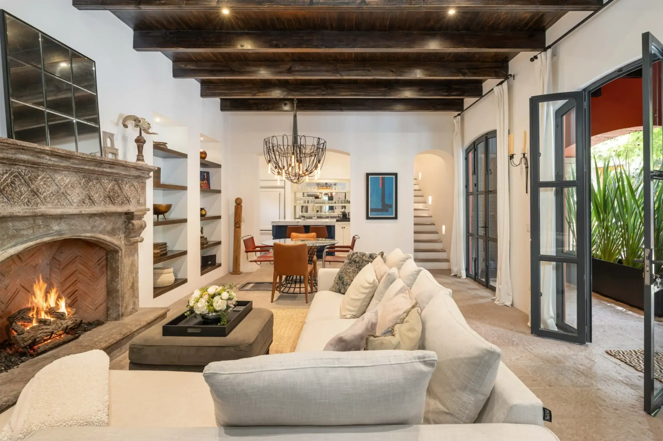 Casa Santa Mónica, living room with a stone fireplace, a white sectional and a beamed ceiling, San Miguel de Allende