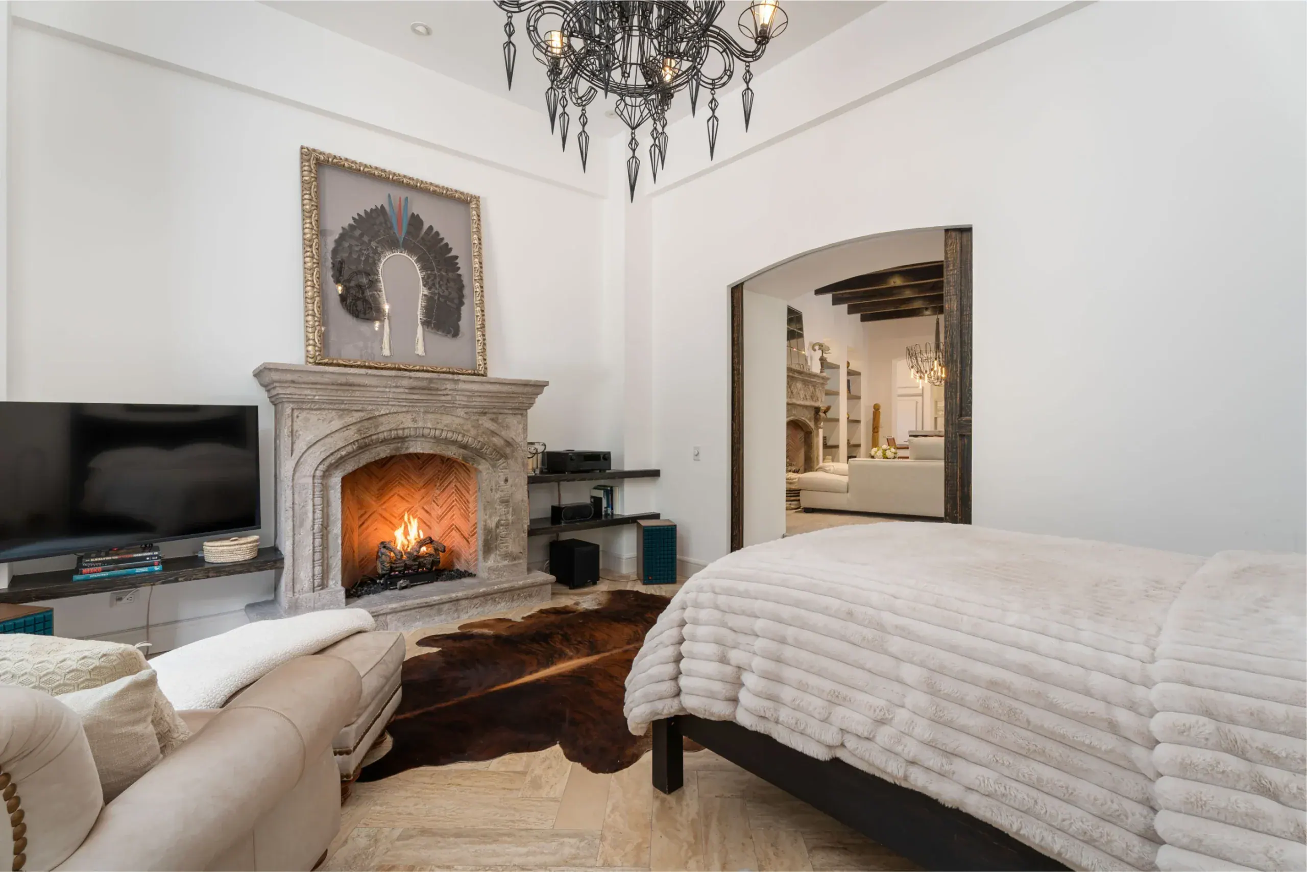 Casa Santa Mónica, bedroom with a stone fireplace, a cowhide rug and a television, San Miguel de Allende