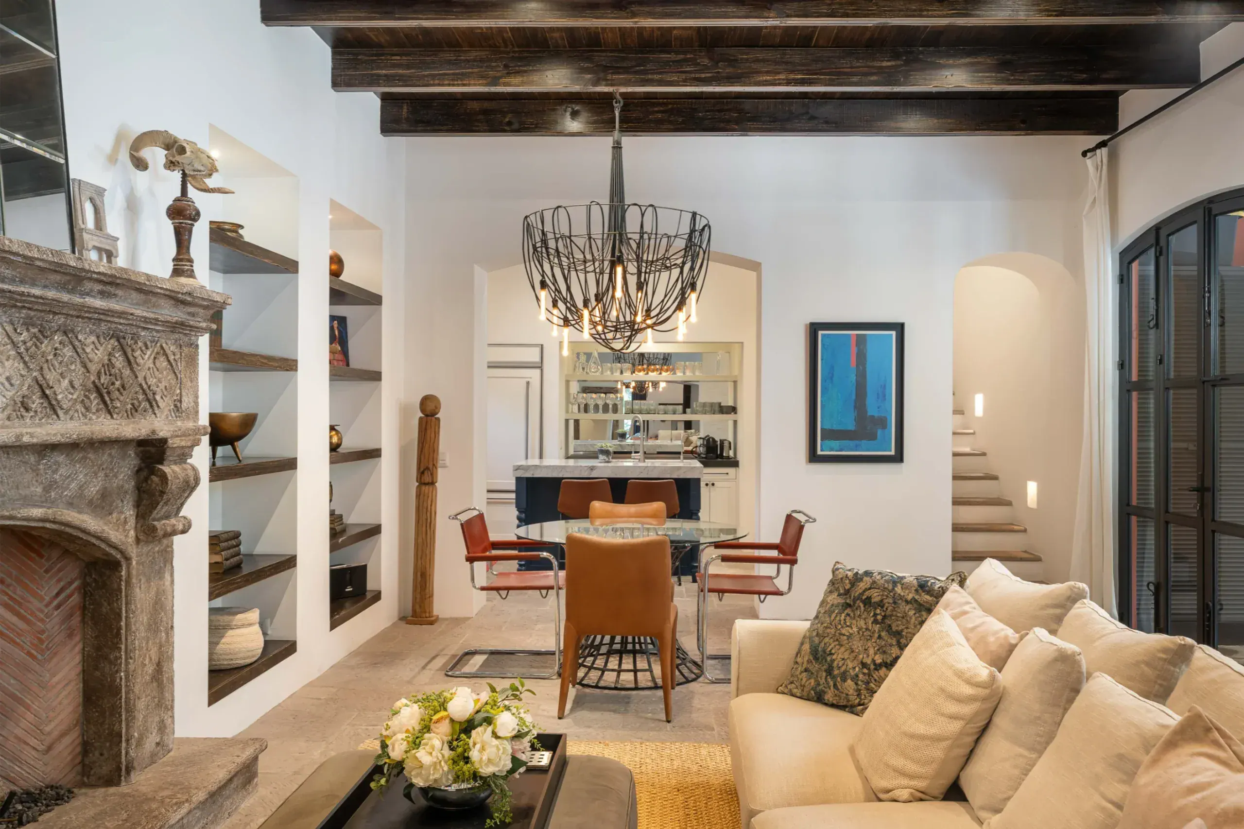 Casa Santa Mónica, dining area with a wrought-iron chandelier beside the stone fireplace, San Miguel de Allende