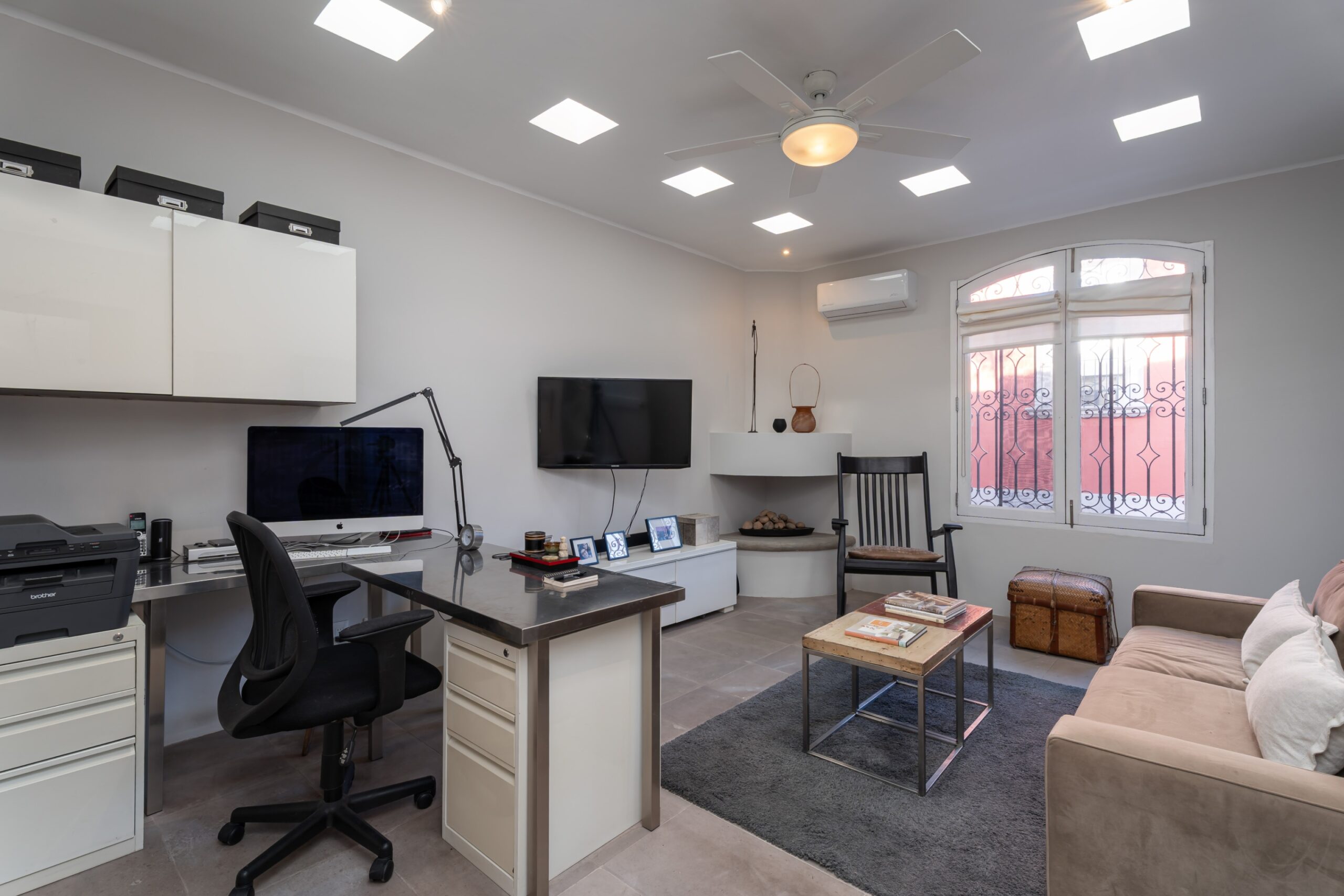 Home office and living room: desk with computer, printer, and white storage cabinets next to a seating area by a window, San Miguel de Allende