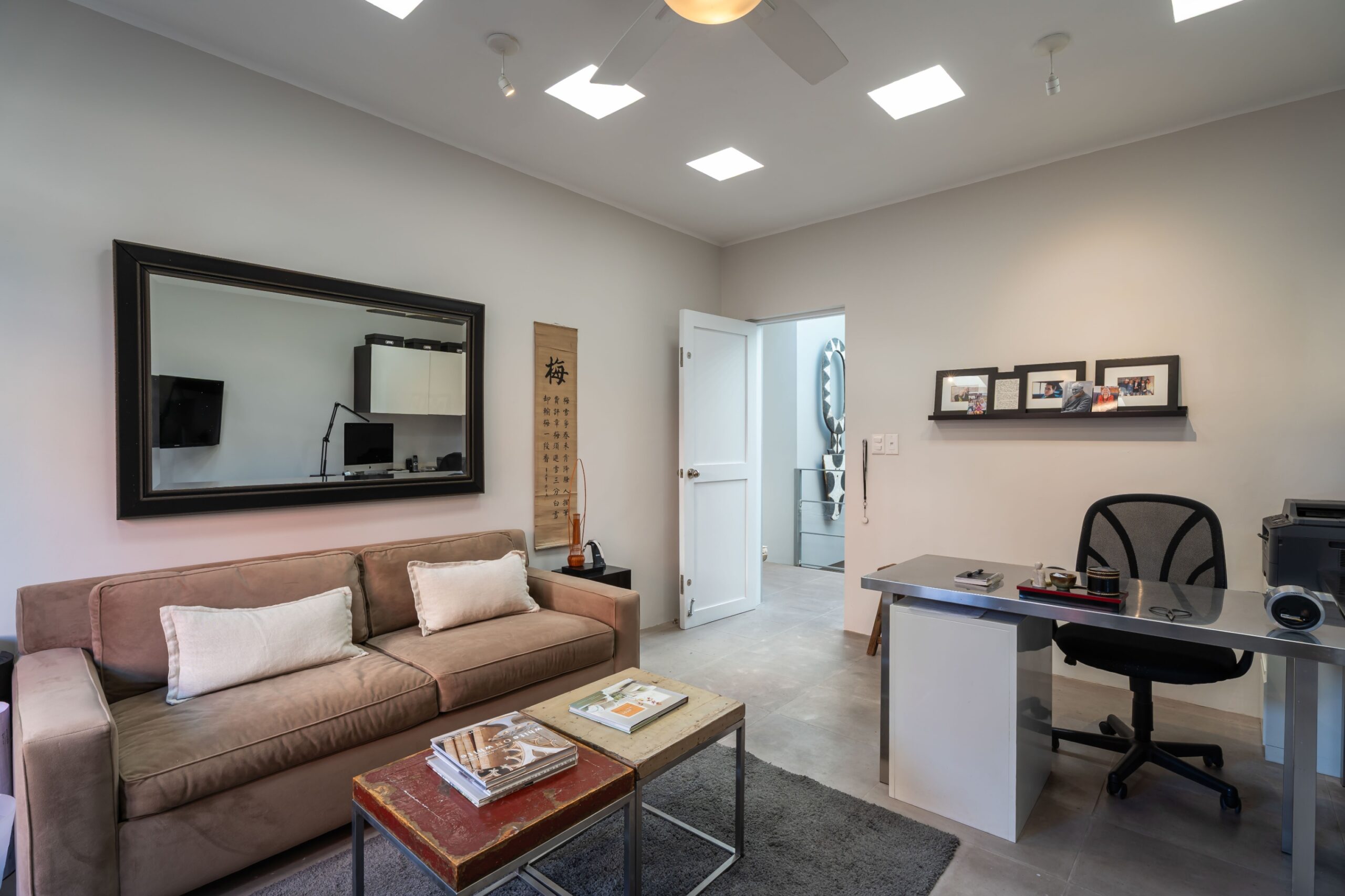 Open-plan office lounge with beige sofa, two coffee tables, and a grey rug, San Miguel de Allende