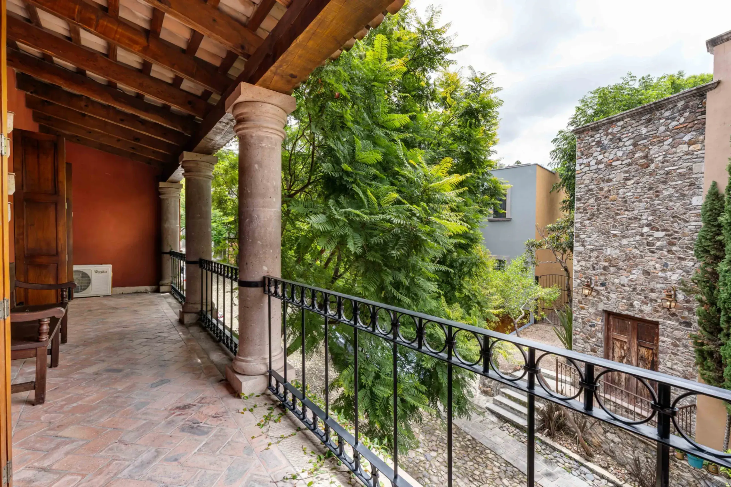 Casa Santa Mónica, covered balcony with stone columns and an iron railing, San Miguel de Allende