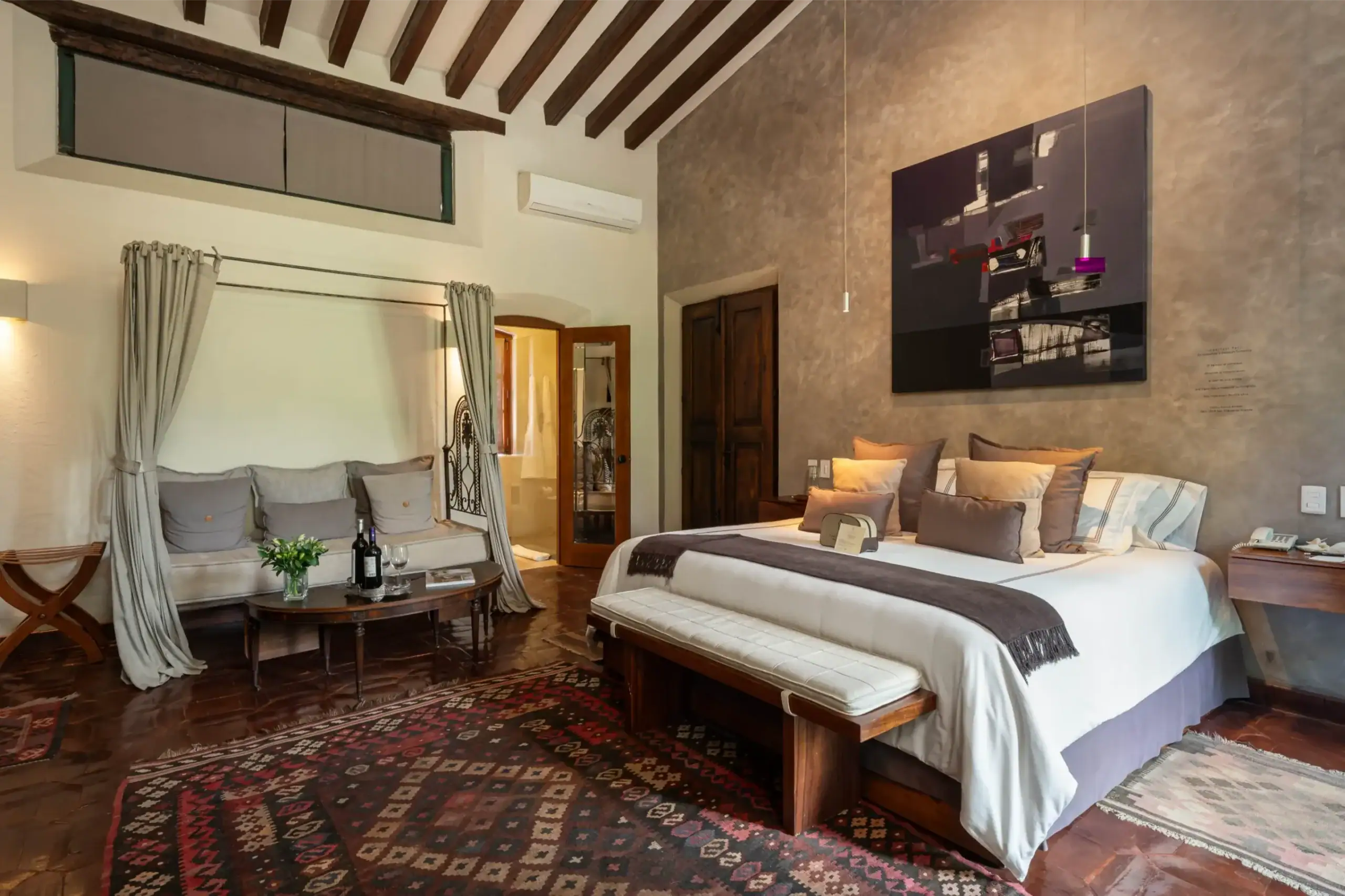 Hotel bedroom with two white beds, brown throw blankets, and a large abstract wall art above the bed, San Miguel de Allende