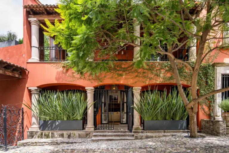 Casa Santa Mónica, orange-red facade with a tree on a cobblestone street, San Miguel de Allende