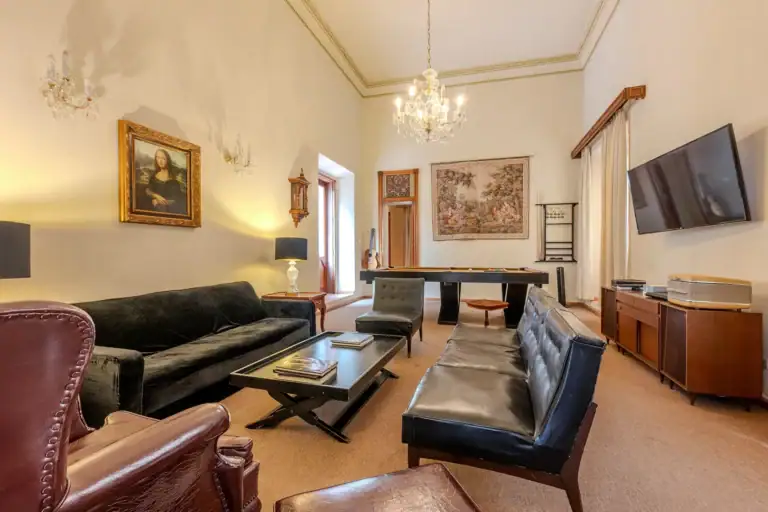Elegant living room with beige walls, crystal chandeliers, and black leather seating around a pool table, San Miguel de Allende