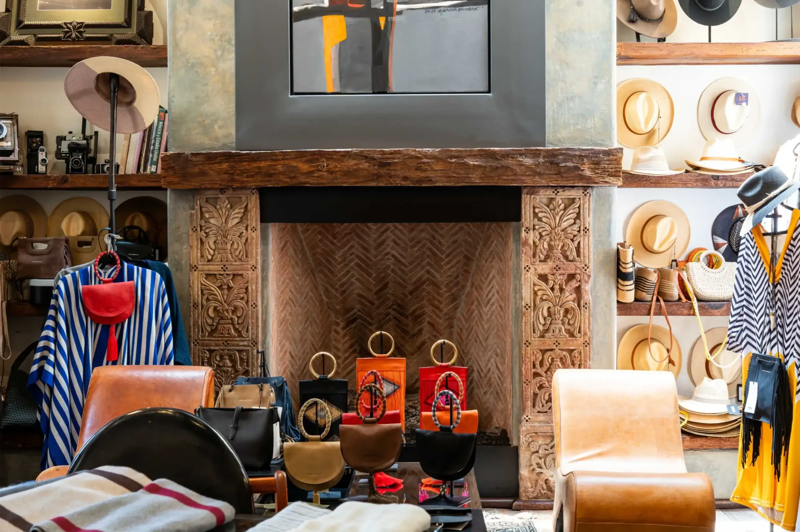 Boutique display of straw hats, handbags, and scarves on wooden shelves around a carved fireplace, San Miguel de Allende