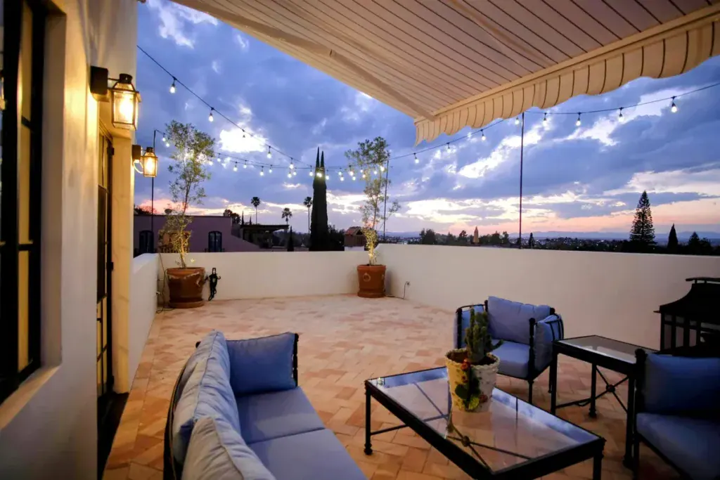 Rooftop terrace with a striped awning, outdoor sofa and string lights at dusk, San Miguel de Allende