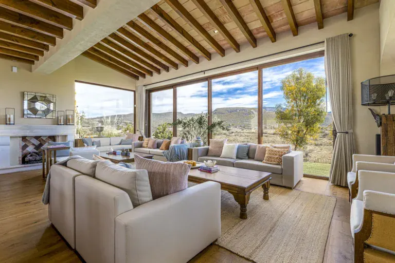 Mañanitas Residence, living room with cream sofas, a fireplace and tall glass doors to the view, San Miguel de Allende