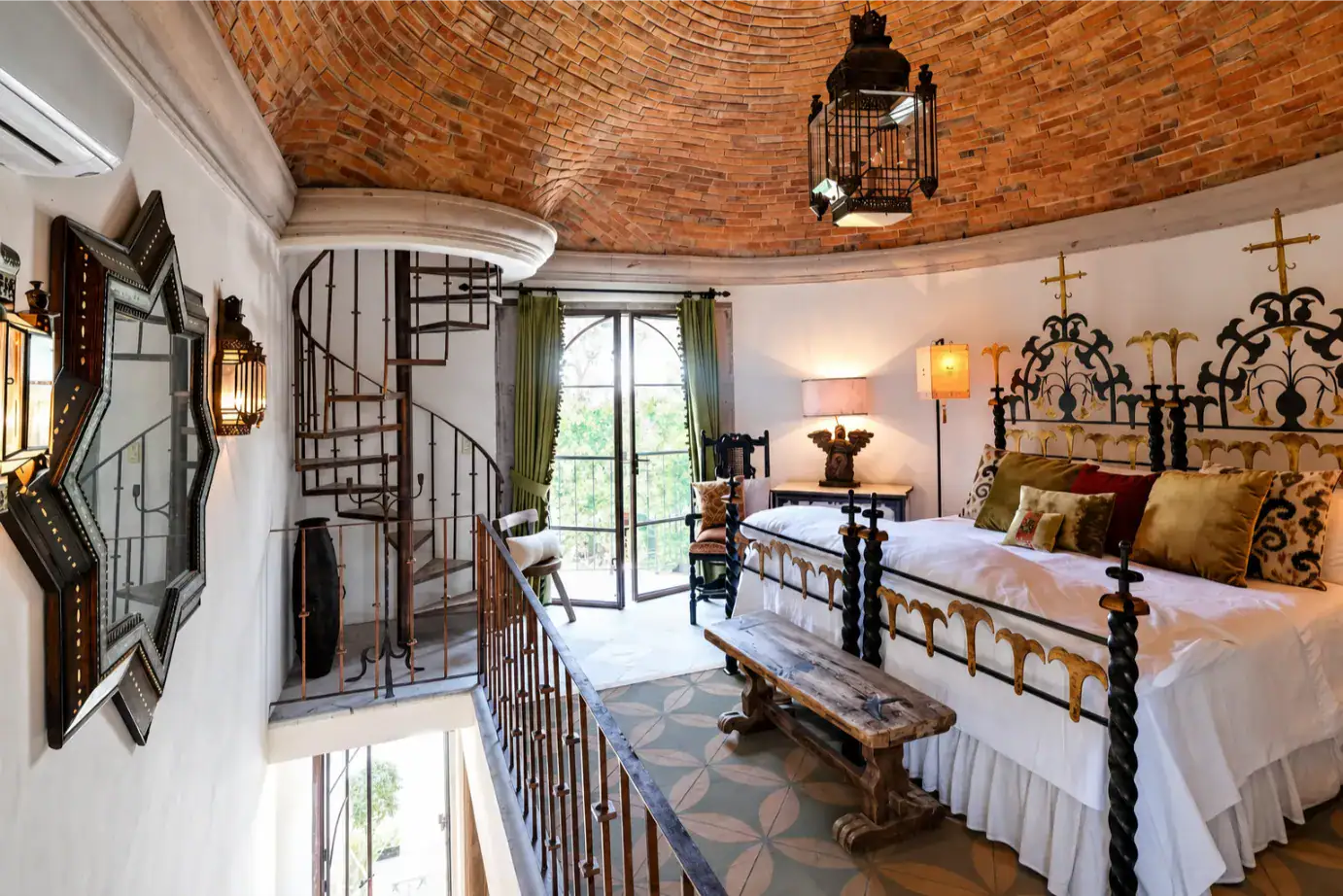 Luxurious turret bedroom with a wrought-iron four-poster bed, brick vaulted ceiling, and a spiral staircase nearby, San Miguel de Allende
