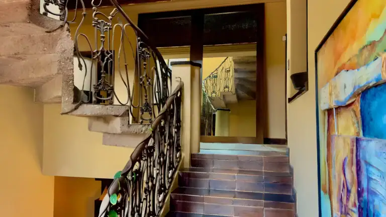 Raíz de las Nubes, wrought-iron spiral staircase and brick steps with a colorful painting, San Miguel de Allende