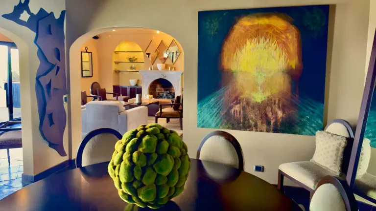 Raíz de las Nubes, dining room with a round dark table and a large glowing orange painting, San Miguel de Allende