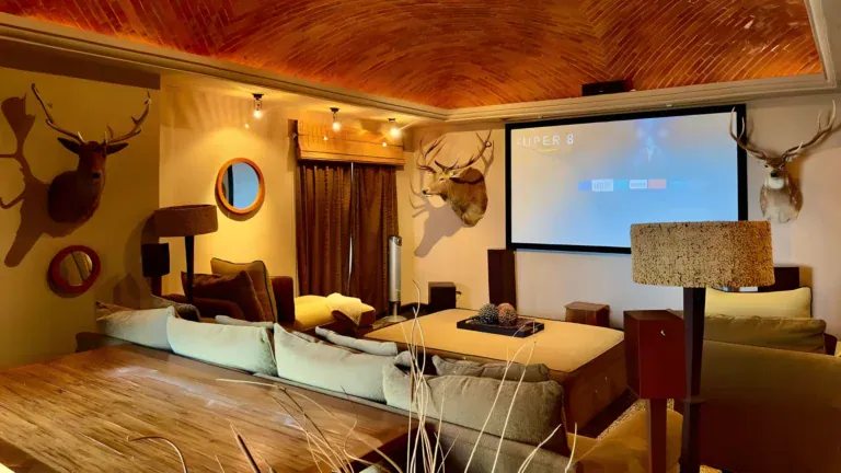 Raíz de las Nubes, media room with a projection screen, sectional seating and mounted deer heads under a brick ceiling, San Miguel de Allende