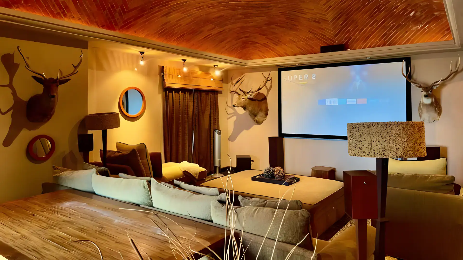 Raíz de las Nubes, media room with a projection screen, sectional seating and mounted deer heads under a brick ceiling, San Miguel de Allende