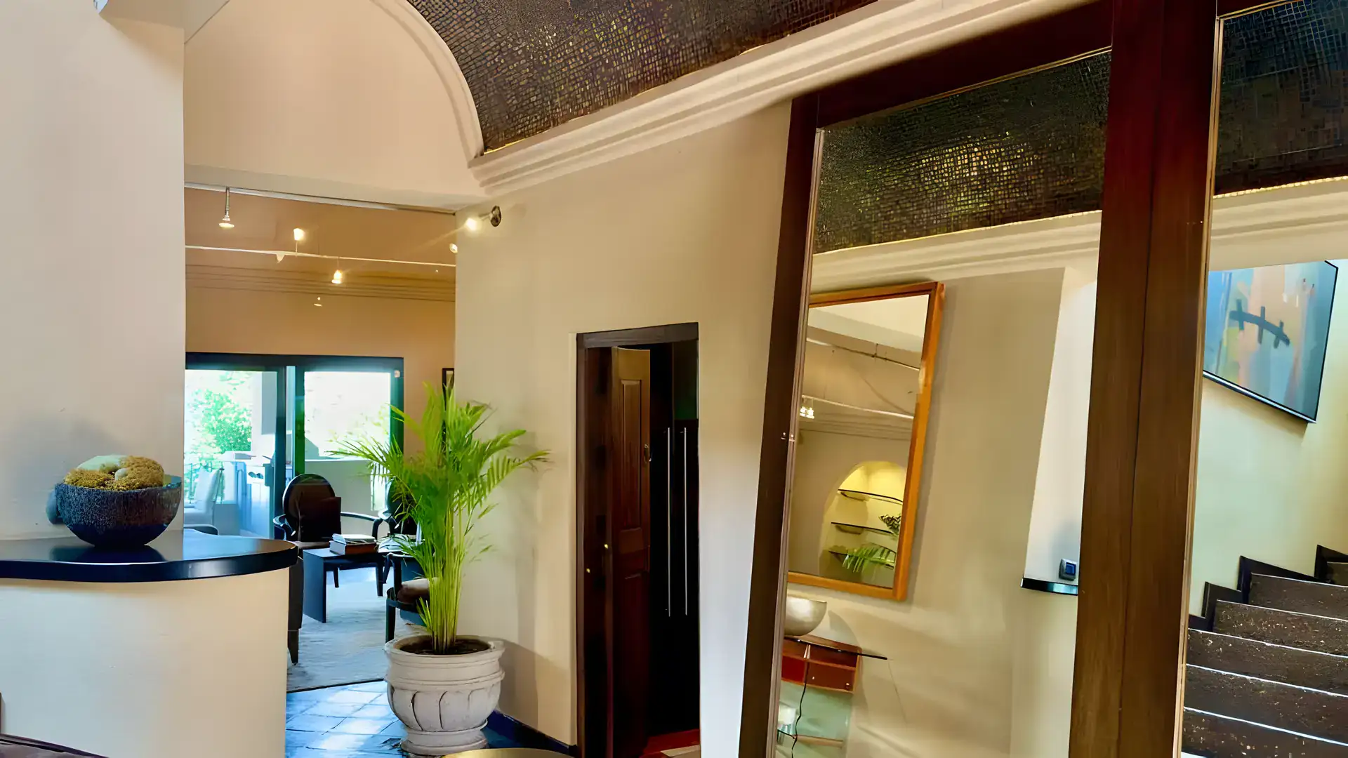Raíz de las Nubes, entry hall with a large mirror, a potted palm and a staircase, San Miguel de Allende